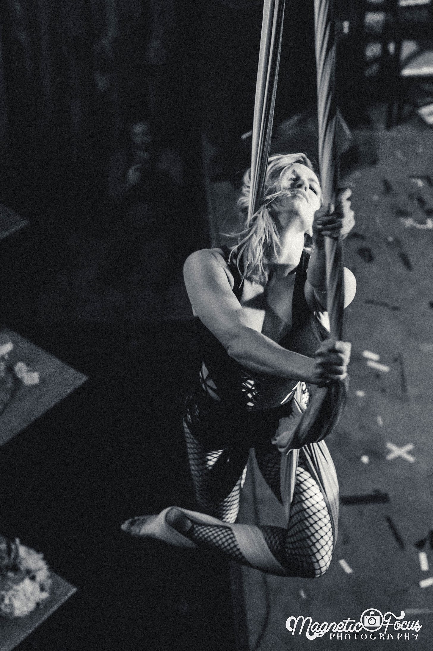 Tolly in fishnets, wrapped in aerial silks, hair wild with an ecstatic expression on her face.