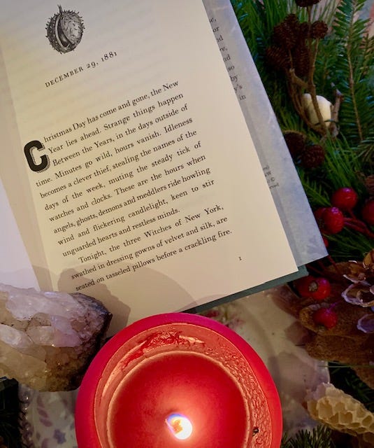 an open book sits on a table next to a lit candle