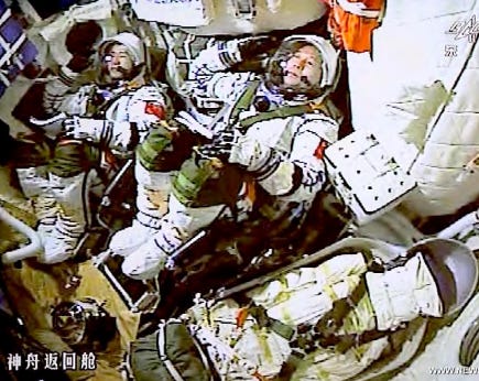 Operator Chen Dong (left) and Commander Jing Haipeng (center), as well as cargo (right) inside the Shenzhou-11 spacecraft during launch.
