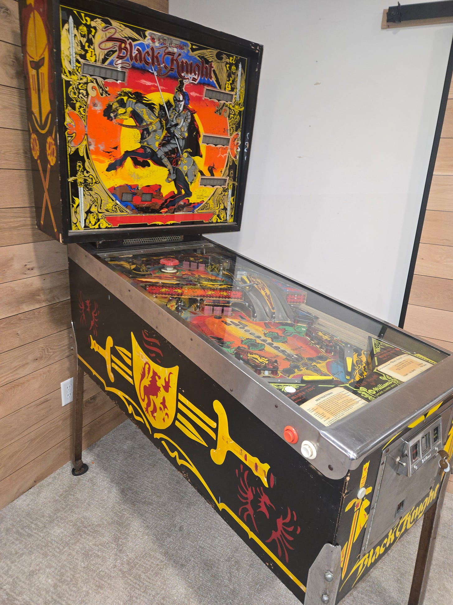 Williams Black Knight (1980) pinball machine with backglass tilted open, showing the playfield and cabinet decorated with sword, shield, and knight artwork Williams Black Knight (1980) pinball machine with backglass tilted open, showing the playfield and cabinet decorated with sword, shield, and knight artwork