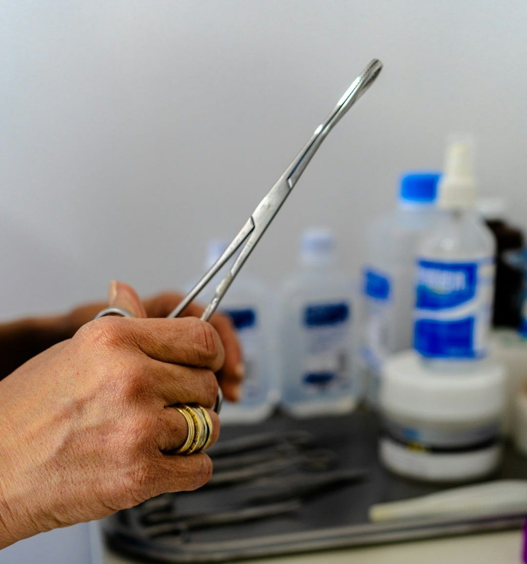 a person holding a pair of scissors over a sink a person holding a pair of scissors over a sink