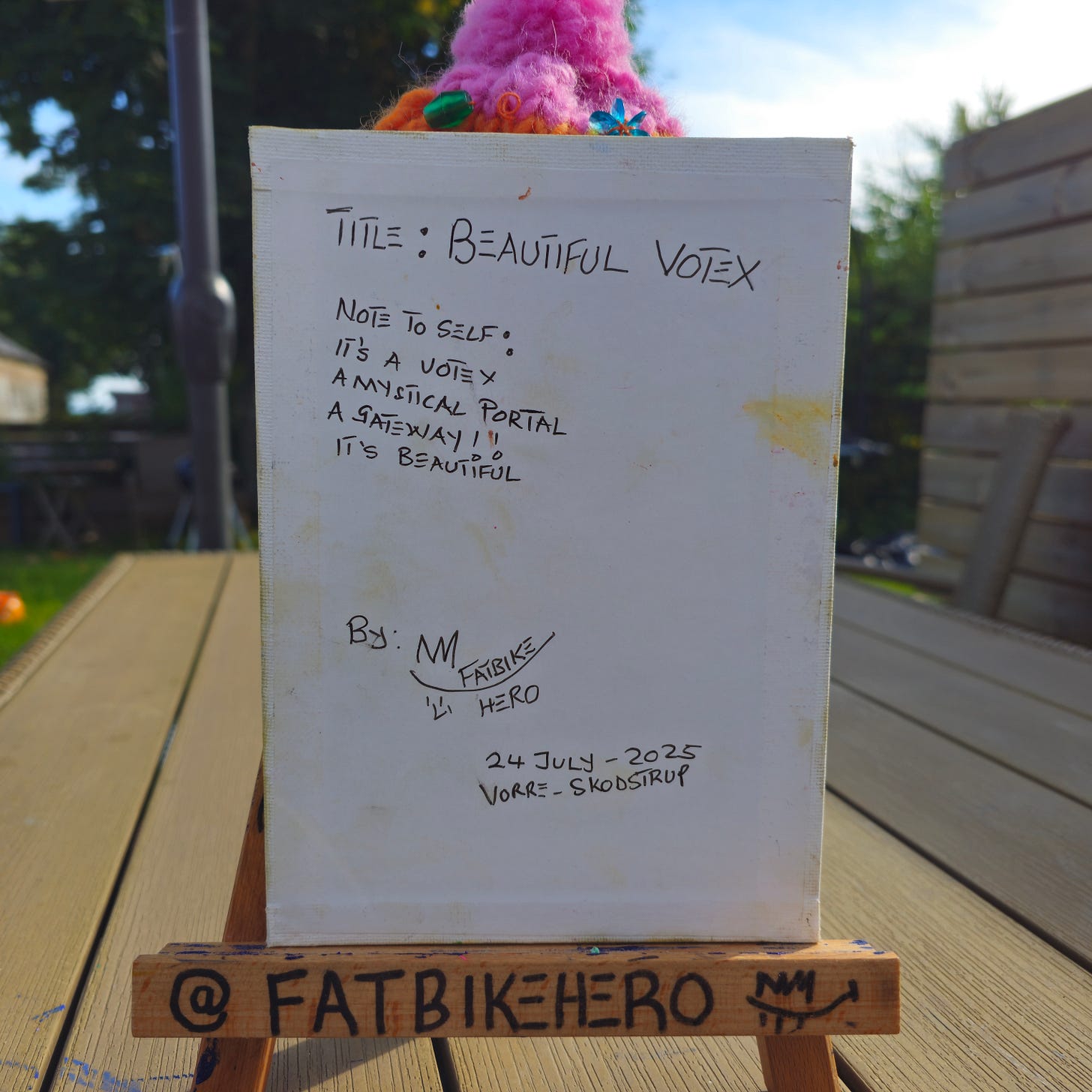 The reverse side of a canvas showing the handwritten title "TITLE: BEAUTIFUL VOTEX" and a note reading: "NOTE TO SELF: IT'S A VOTEX, A MYSTICAL PORTAL, A GATEWAY!! The reverse side of a canvas showing the handwritten title "TITLE: BEAUTIFUL VOTEX" and a note reading: "NOTE TO SELF: IT'S A VOTEX, A MYSTICAL PORTAL, A GATEWAY!!