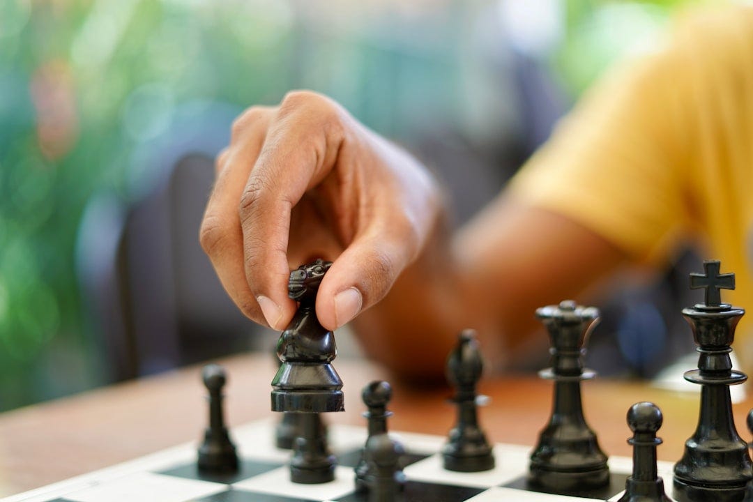person holding black and silver chess piece person holding black and silver chess piece