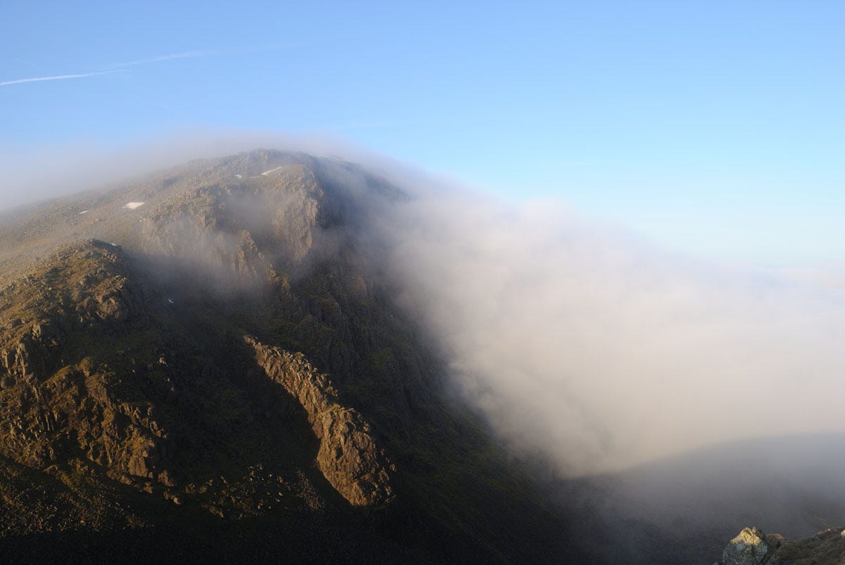 sunlit crags left, half clouded hill right
