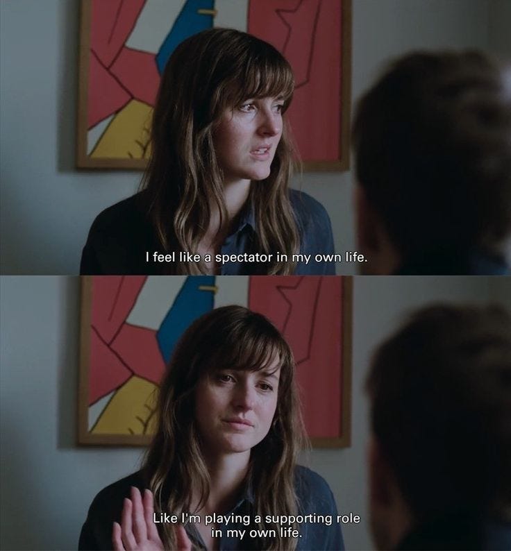 This may contain: a woman with long hair and bangs talking to another woman in front of a painting This may contain: a woman with long hair and bangs talking to another woman in front of a painting