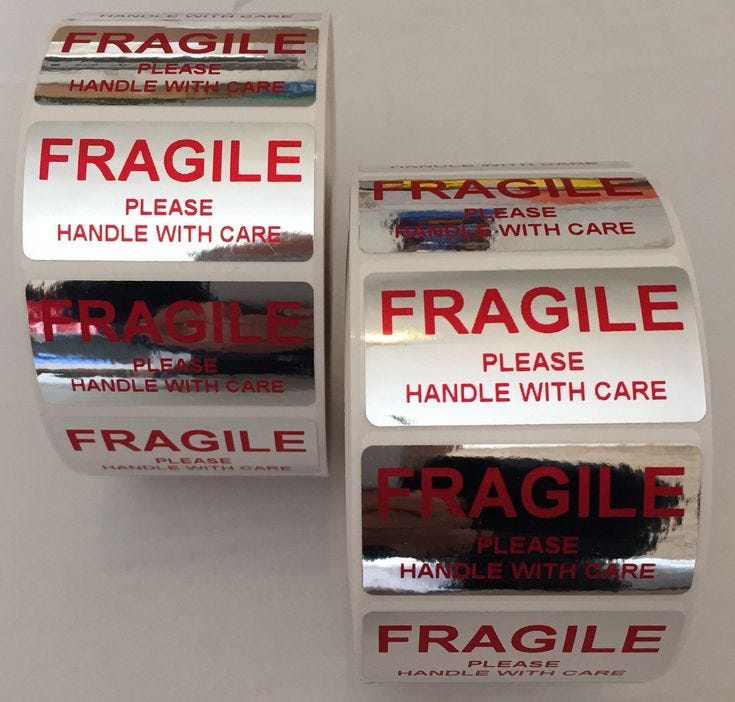This may contain: three rolls of fragile labels on a white surface with the words fragile and handle with care