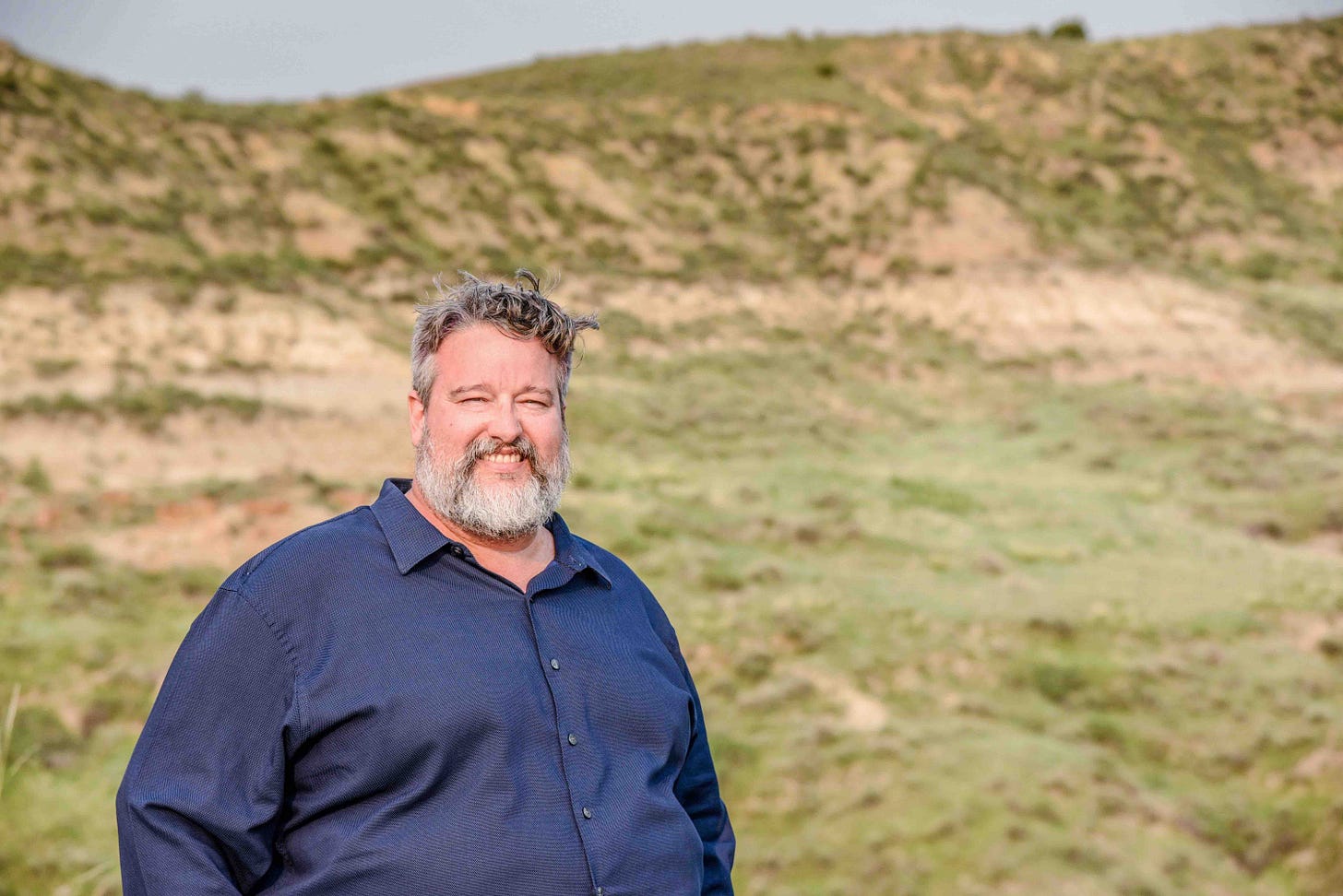 man in blue shirt near grassy rise