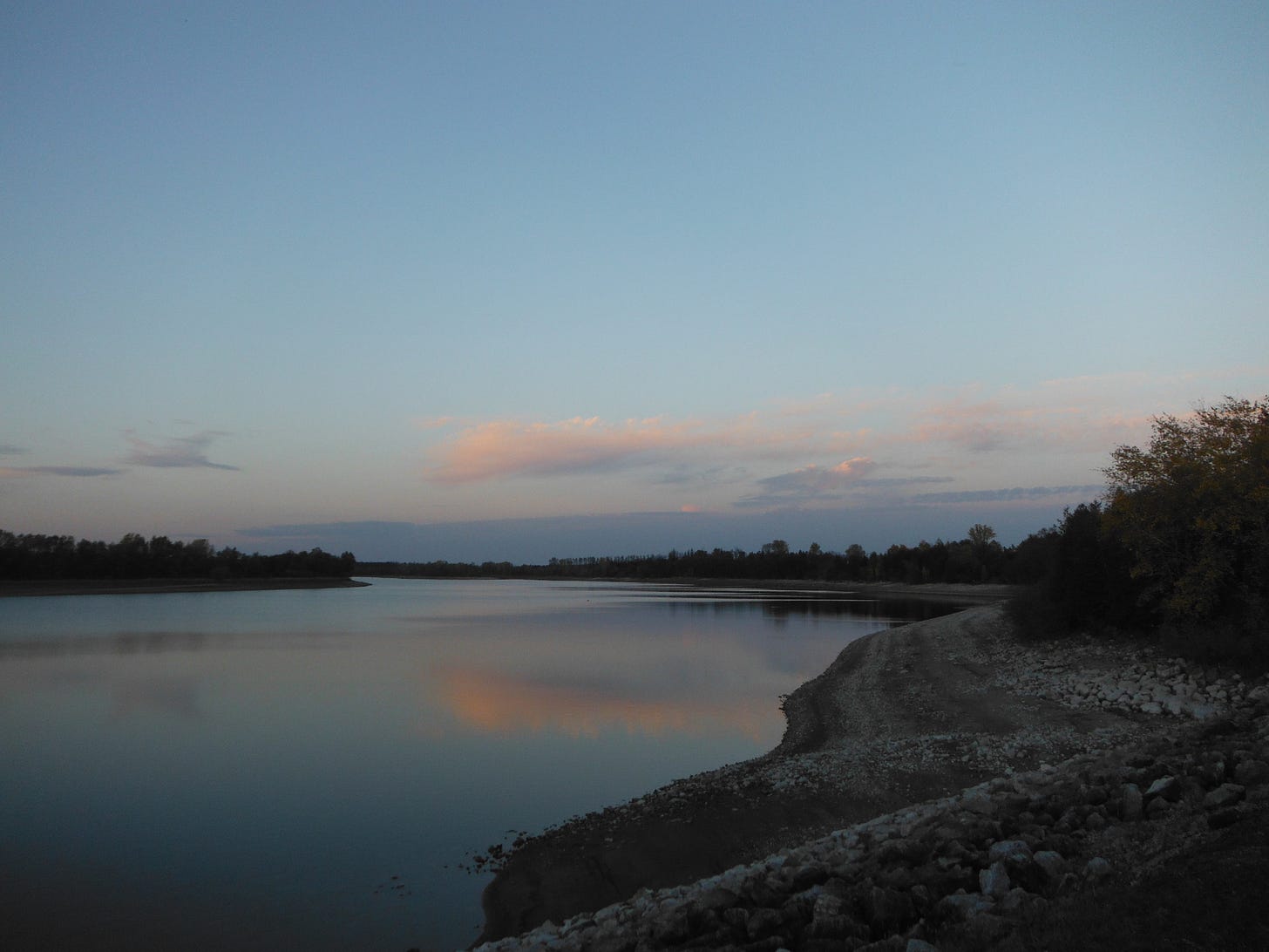 A still lake with a curving, rocky shore