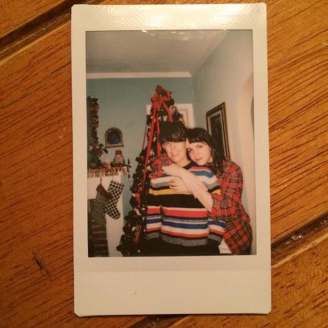 A series of photos of Andrea and Meg on Christmases throughout the years, usually featuring trees, lights, Santa outfits, and dogs in festive sweaters. There are also two red holiday mugs, one that says "Hers", and its pair, that says, "Theirs"