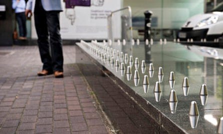 A photo of spikes on a low bench-like structure, with people standing in the background blurred out A photo of spikes on a low bench-like structure, with people standing in the background blurred out