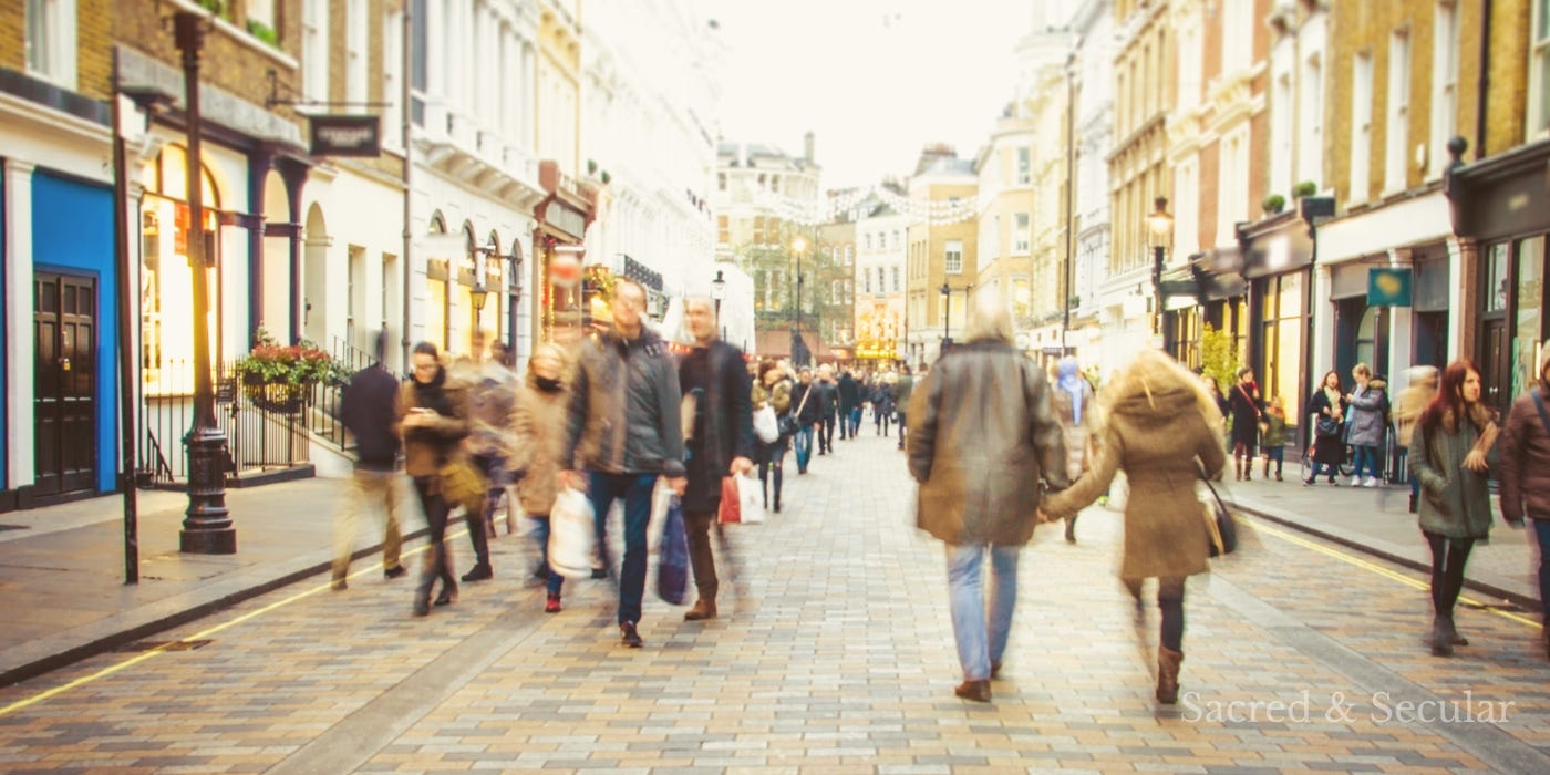 A busy pedestrian street lined with shops, where people walk past one another in soft afternoon light. The scene captures the movement and anonymity of everyday life in a town centre. A busy pedestrian street lined with shops, where people walk past one another in soft afternoon light. The scene captures the movement and anonymity of everyday life in a town centre.
