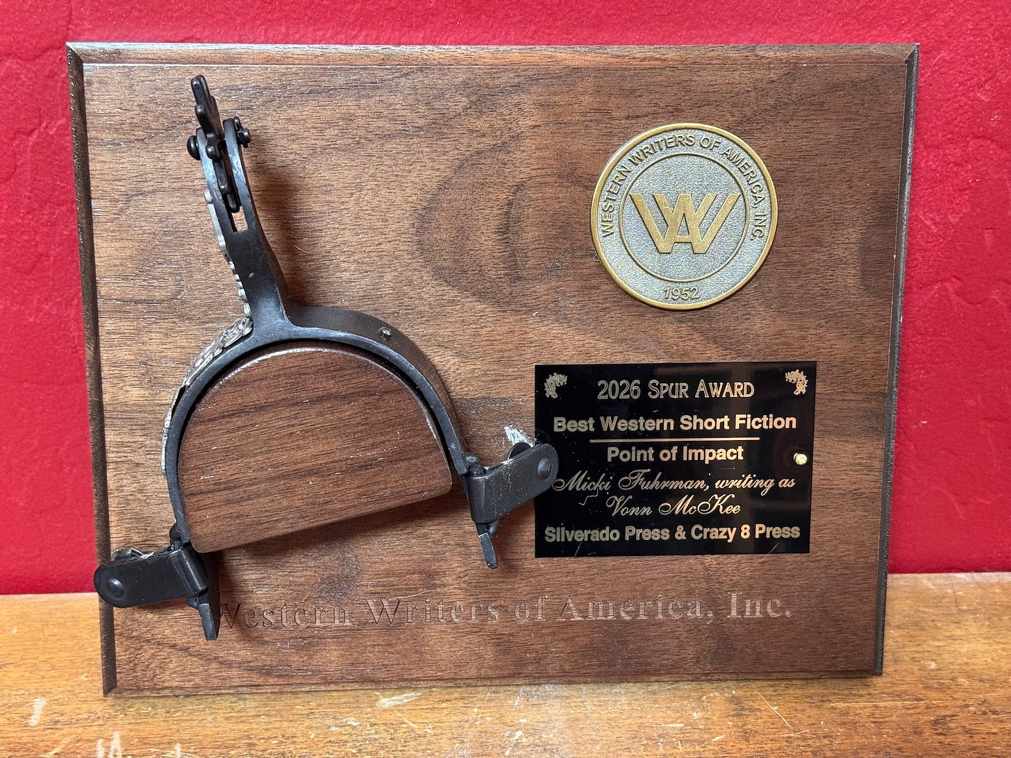 A wooden plaque with a spur mounted on it, the seal of the Western Writers of America, and the title of the story that won the award