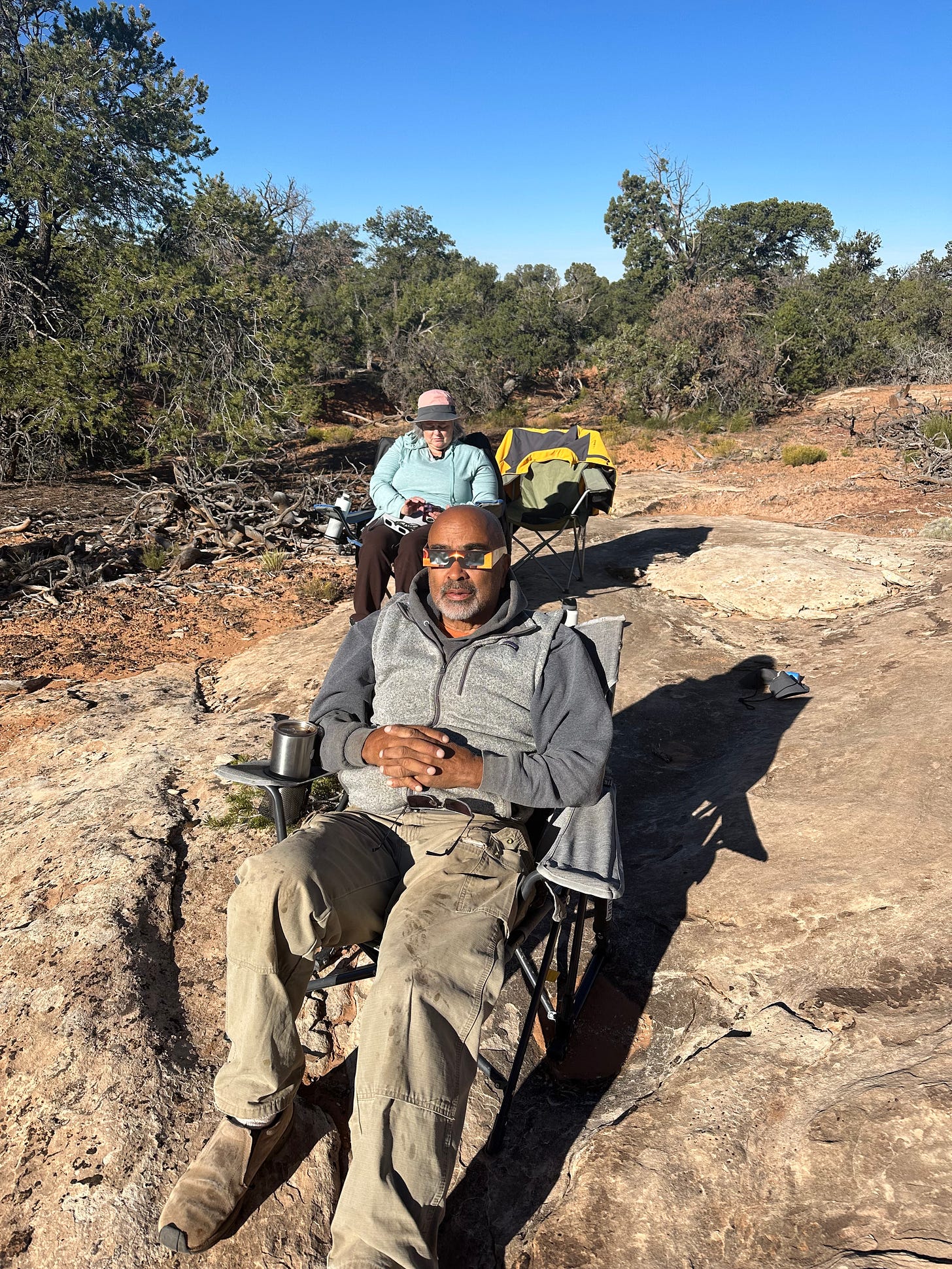 A person sitting in a chair on a rocky hill

Description automatically generated
