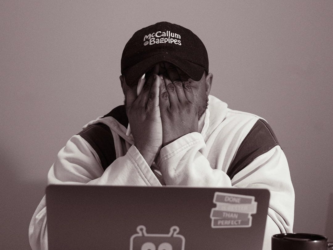 Person with hands over face at laptop