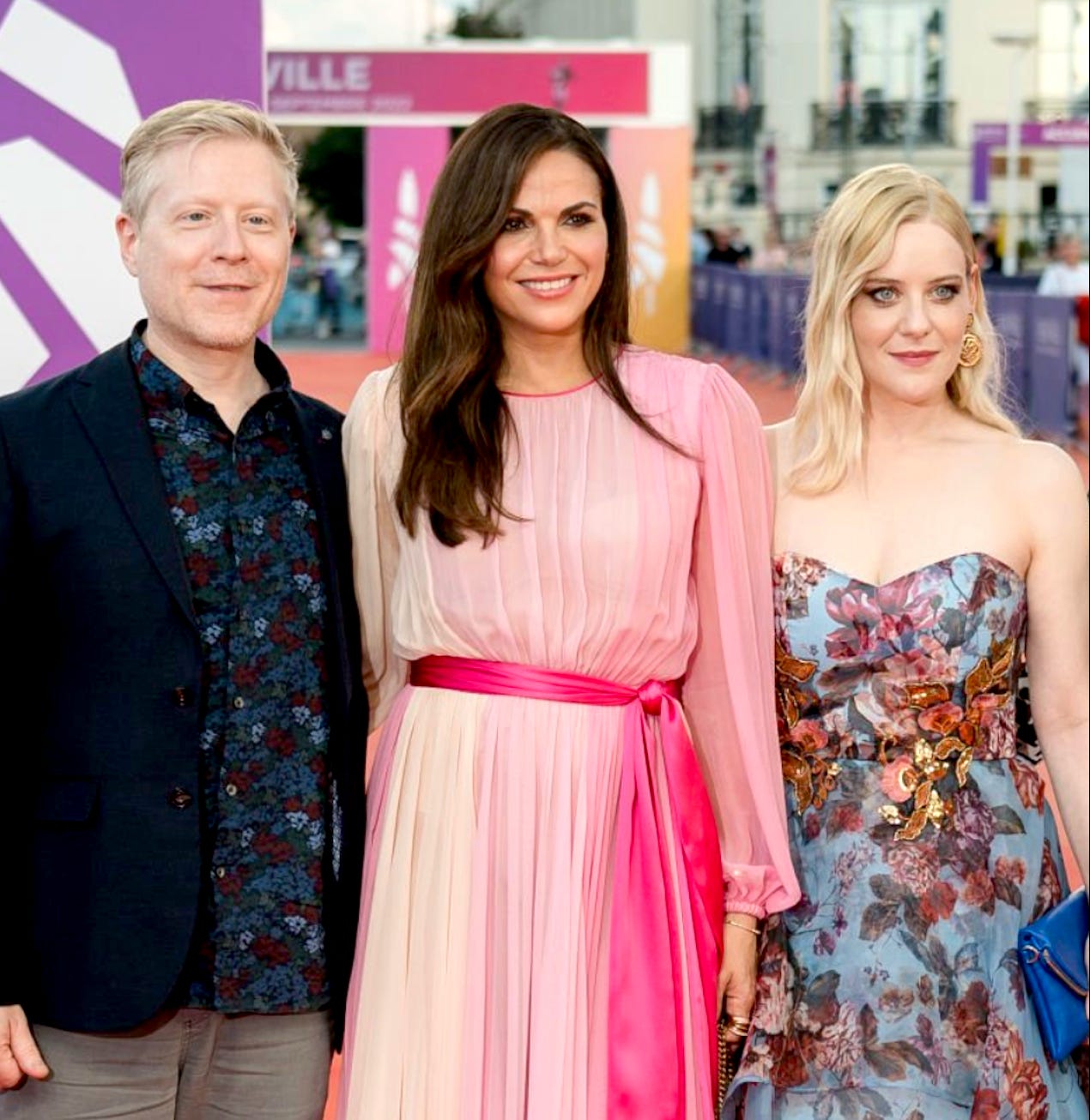 A man and two women stand together A man and two women stand together