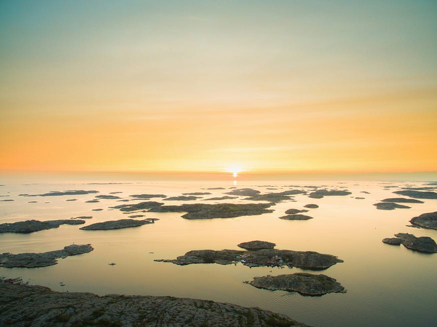 A calm seascape with the sun setting over it.