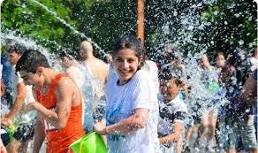 Celebration of Vardavar in Armenia with girl wearing white t-shirt throwing waiter with a green pail