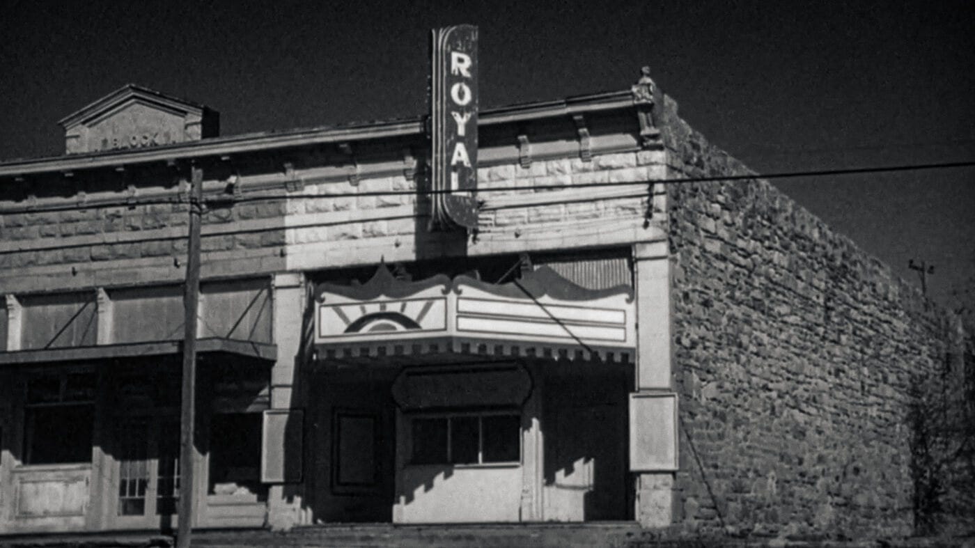 Black-and-white image of the Royal Theater from The Last Picture Show, its facade worn and abandoned beneath a sun-faded marquee.