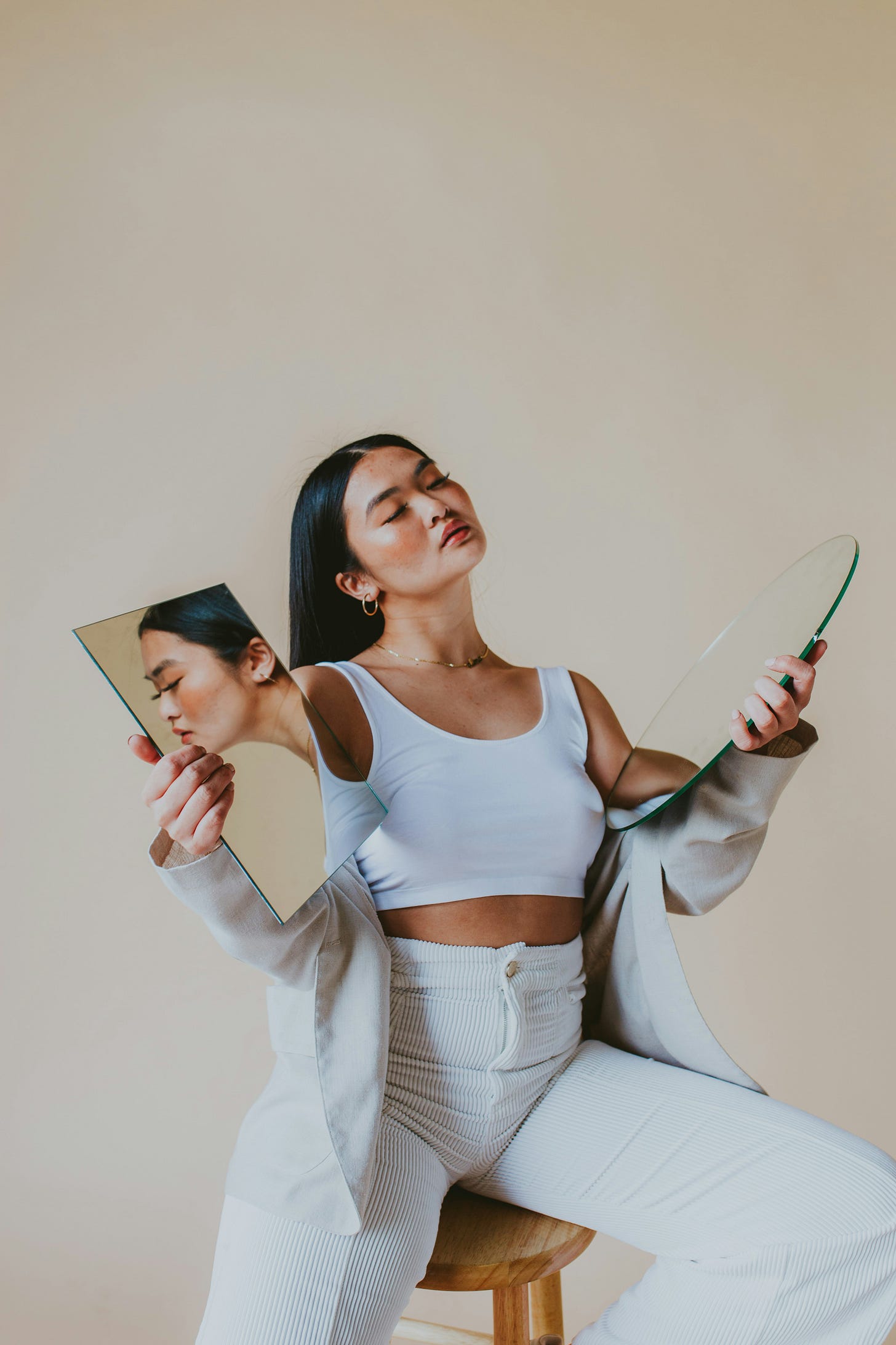 a woman holding two mirrors, one shows the reflection of her face