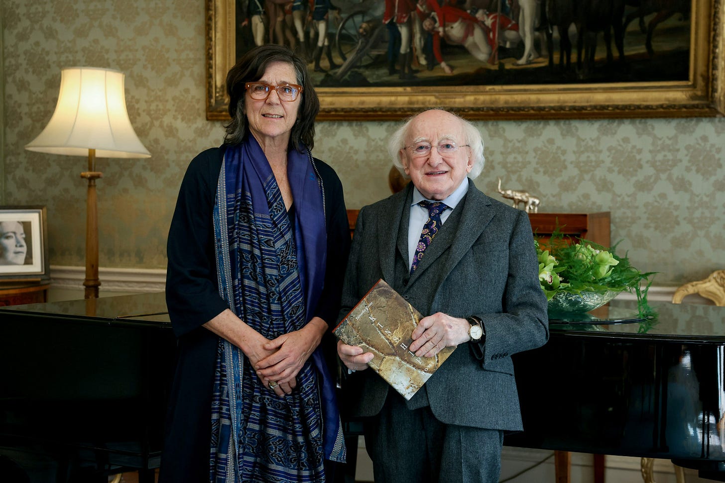 The Irish artist Dorothy Cross standing beside Ireland's President Michael D. Higgins in a formal reception room.