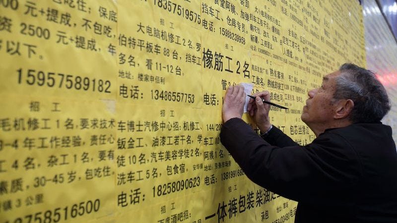 Elderly Chinese migrant worker looking at job ads on a wall Elderly Chinese migrant worker looking at job ads on a wall