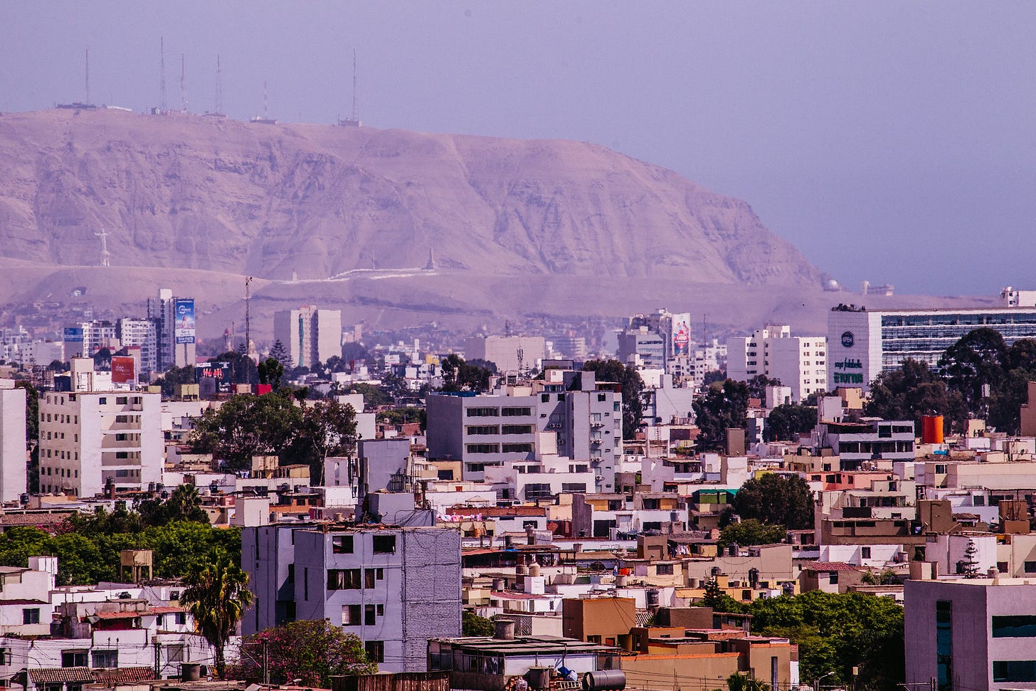View from high above Mexico City; city rooftops with distant hazy hills under a moody sky
