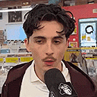 a young man with a mustache is talking into a microphone in a store .