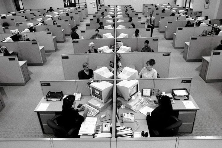 This may contain: an office filled with cubicles and people working on computers