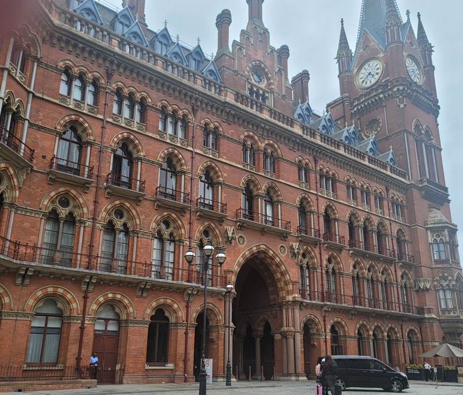 A large brick building with a clock tower with St Pancras railway station in the background

AI-generated content may be incorrect.