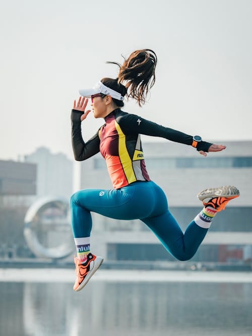 Free A woman in a running outfit jumping in the air Stock Photo