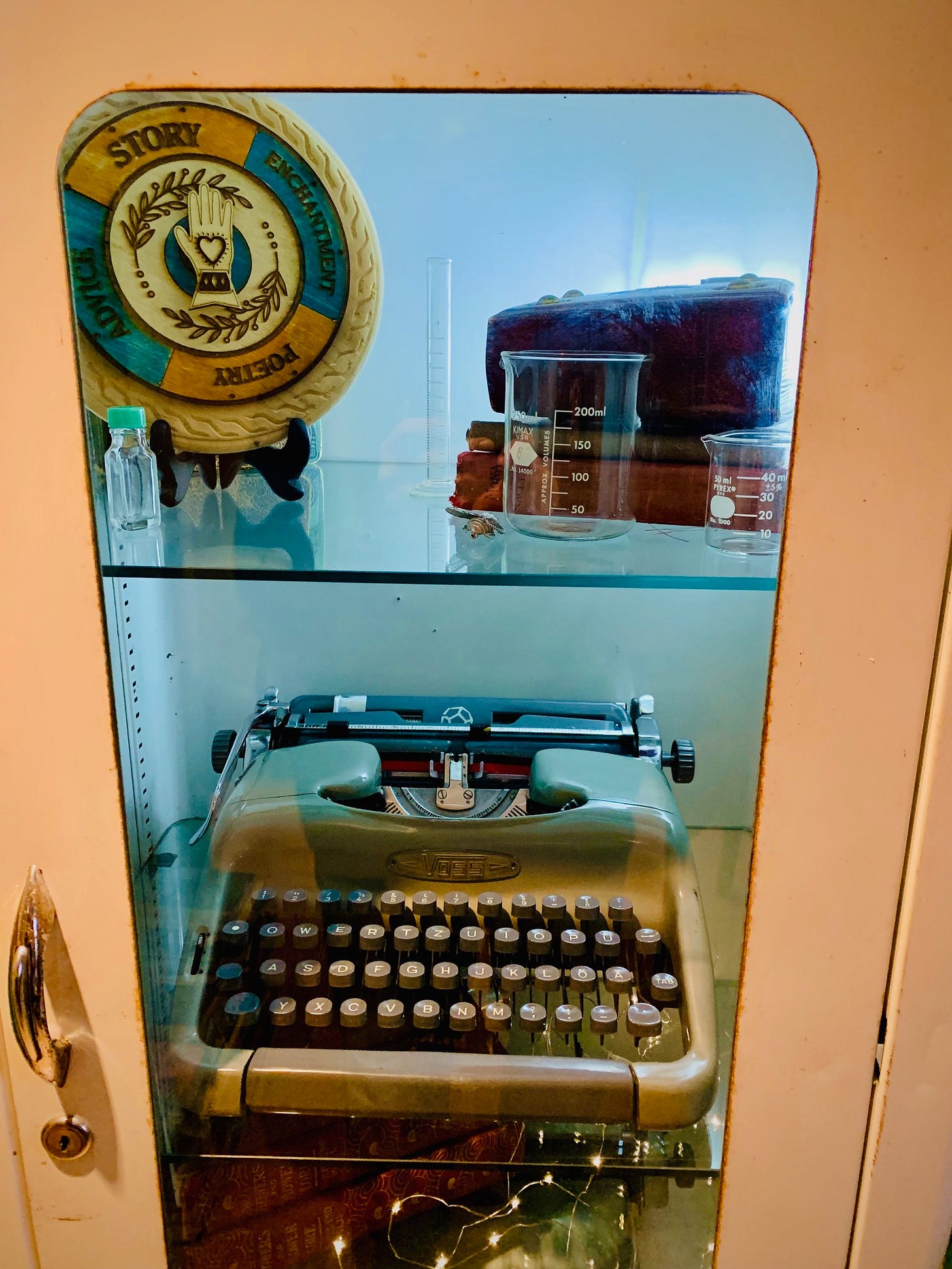 an old medicine cabinet contains books, beakers, medicine bottles, a typewriter and a wheel of destiny