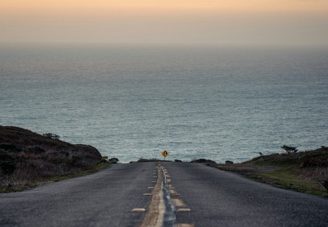 black asphalt road beside body of water during daytime