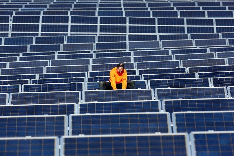 Worker inspecting solar panels in a large-scale solar farm in Spain amid controversies over government subsidy cuts