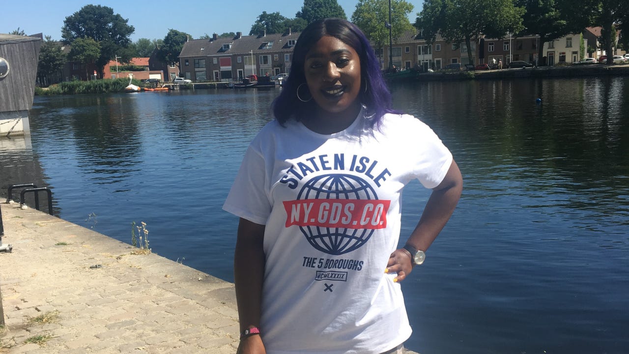 Black woman with purple hair standing in front of a canal in the Netherlands