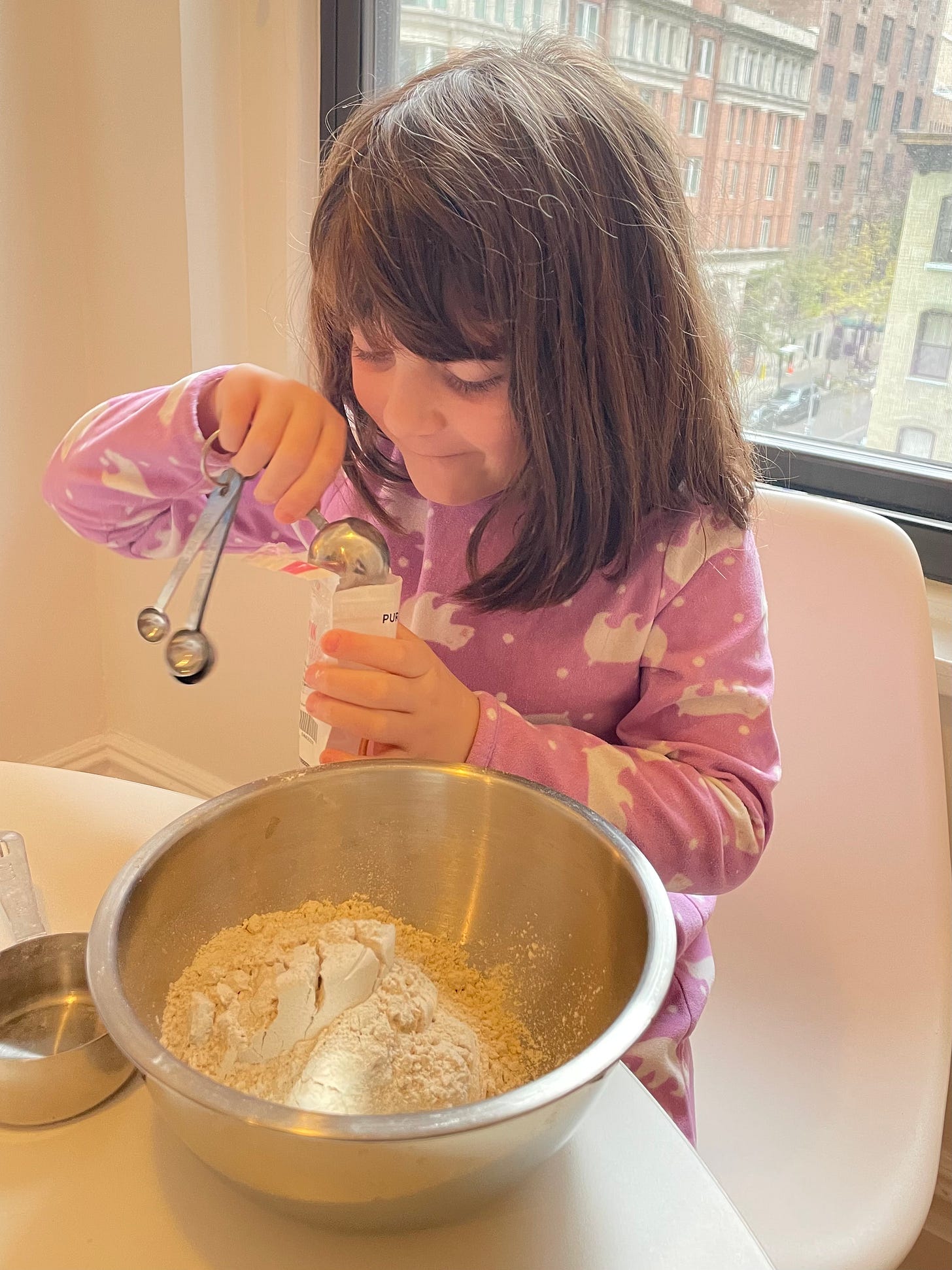 Little girl measuring ingredients for pancakes