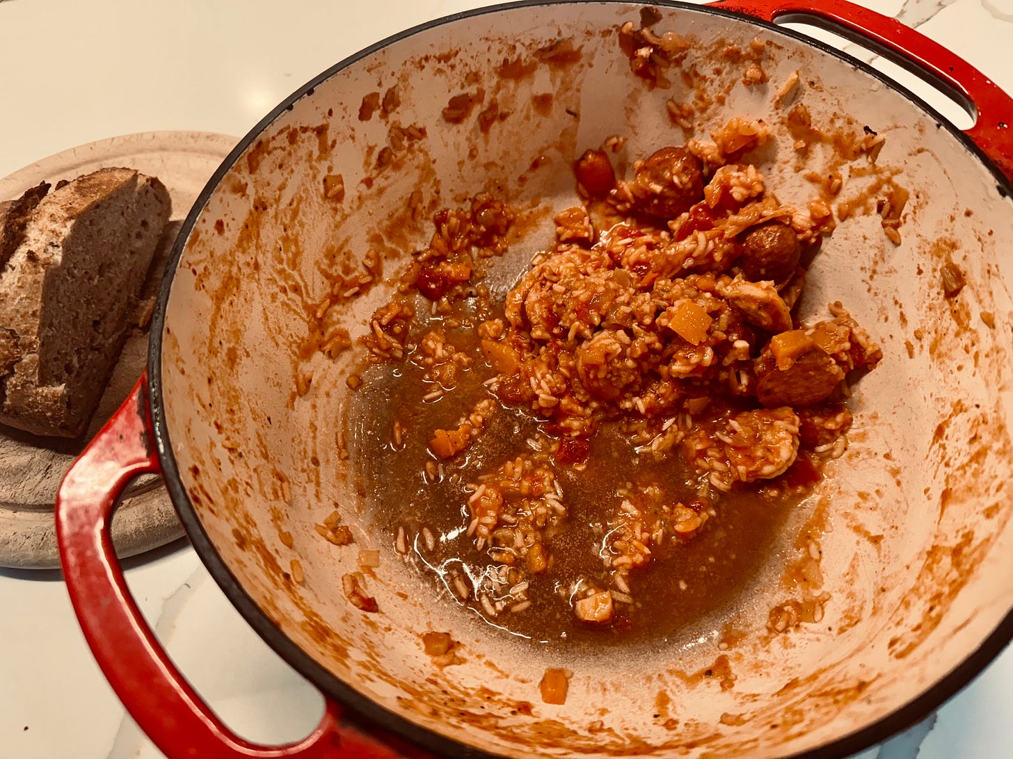 Dutch oven that is nearly emptied of the jambalaya it once held.