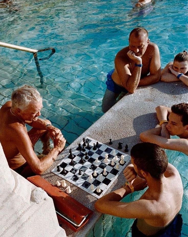 This may contain: four men playing chess in a swimming pool
