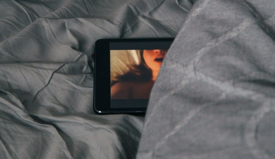 black Android smartphone on gray bed sheet