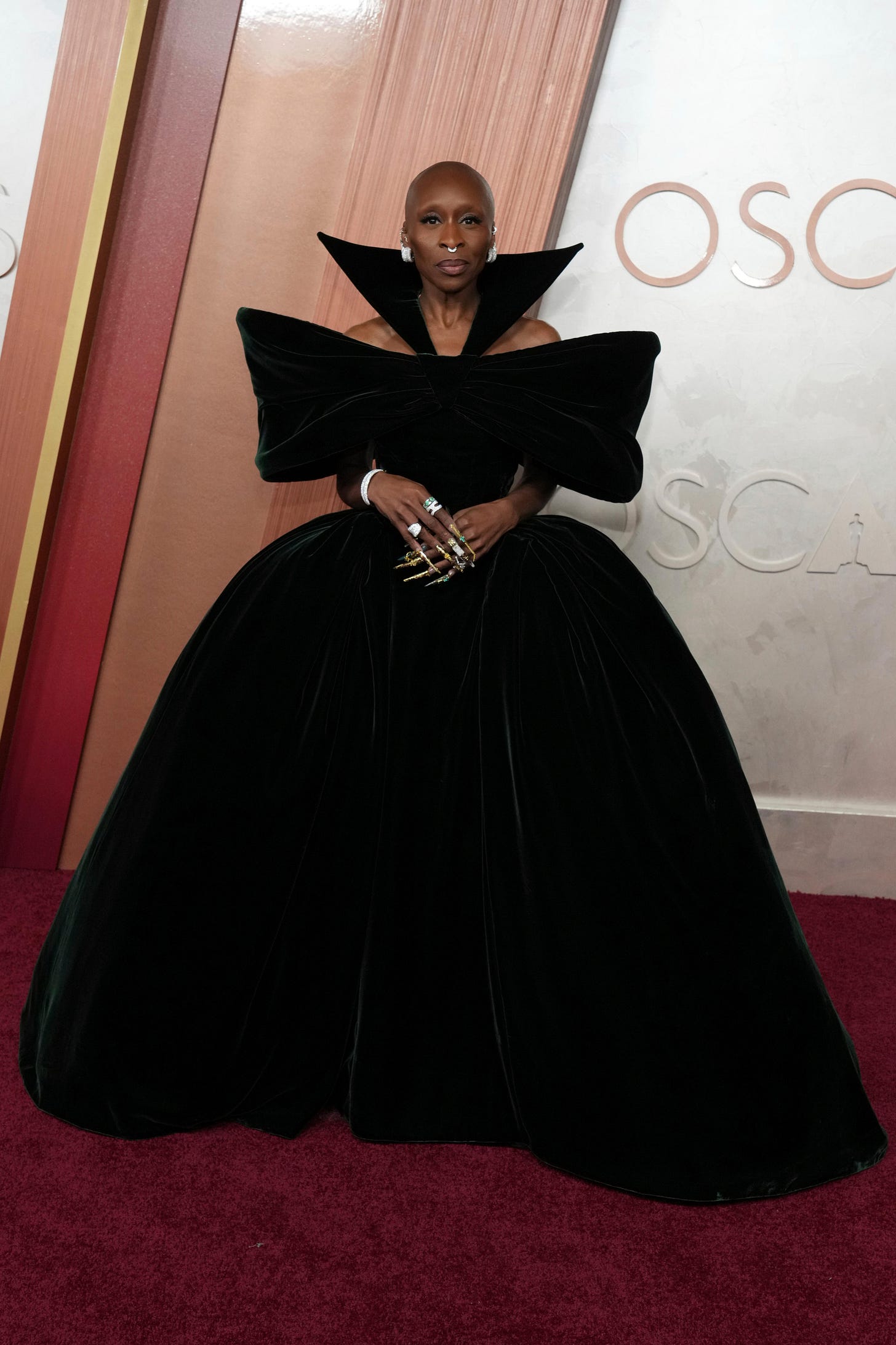 Cynthia Erivo wearing a dark green full-length gown with wide shoulders and a sharp collar