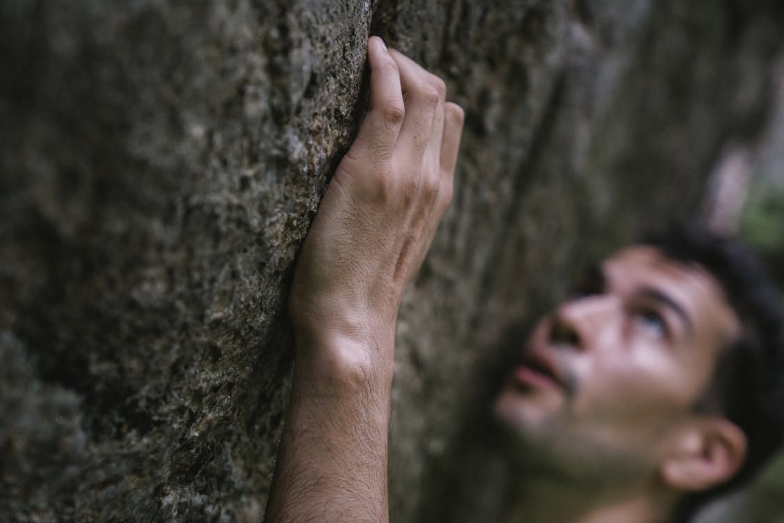 Free Close-up of a man climbing a rock face with focus and determination. Stock Photo