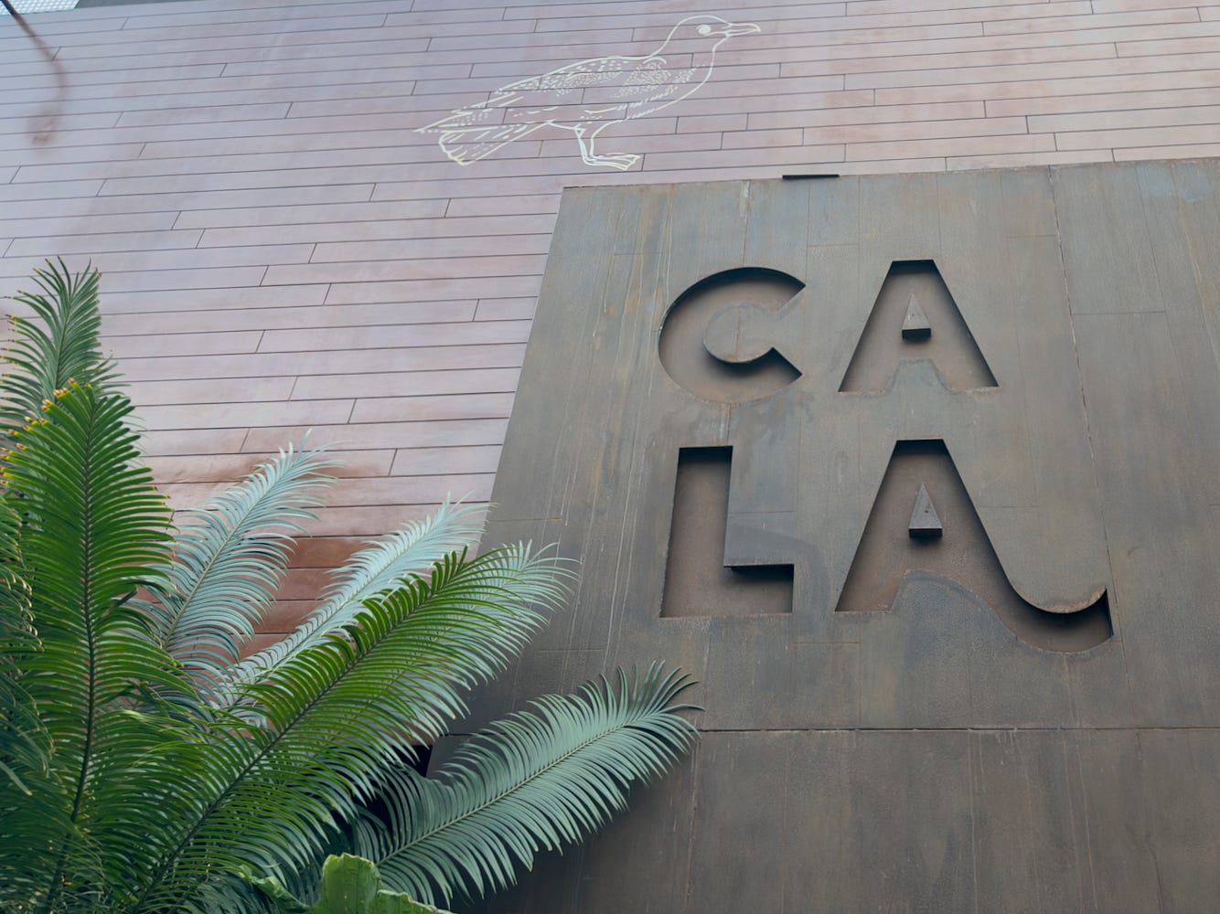 A large sign and a stencil of a bird greets visitors to Cala in Miraflores, Lima