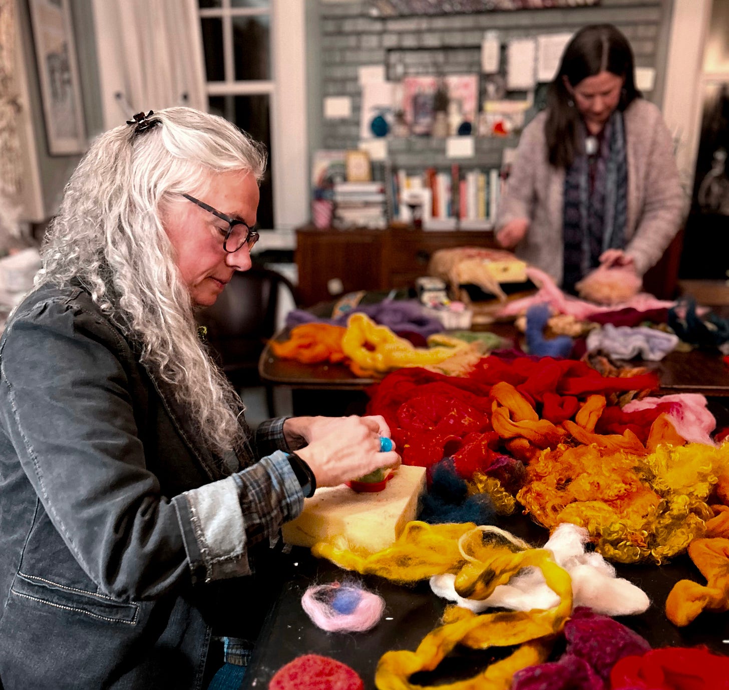 An image of two women at a table crafting with felted wool.