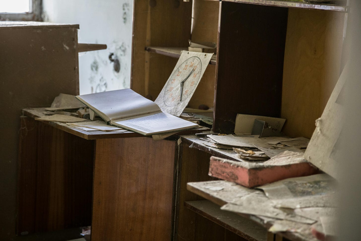 An open book on a brown wooden desk near piles of papers An open book on a brown wooden desk near piles of papers