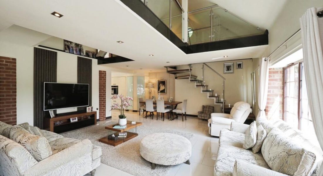 A living room with white walls and black panelling, a TV, and grey sofas and a rug A living room with white walls and black panelling, a TV, and grey sofas and a rug