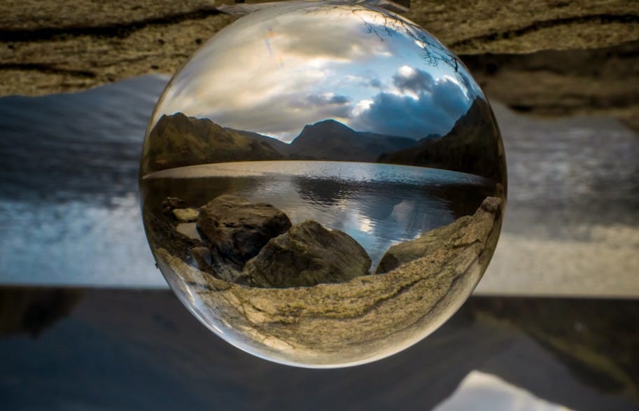 clear glass ball on white sand during daytime clear glass ball on white sand during daytime