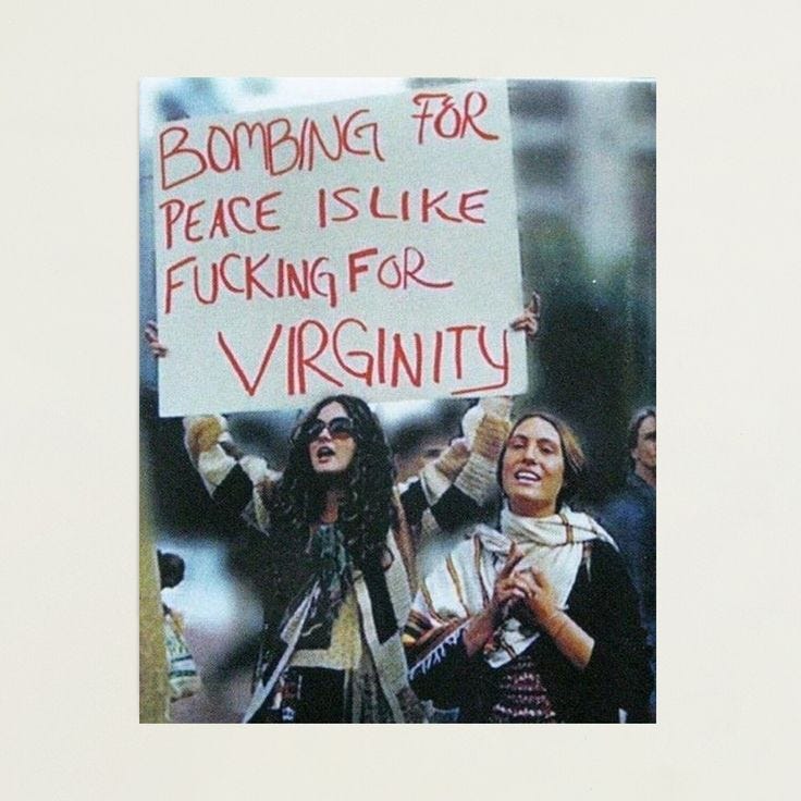 This may contain: two women holding up signs in front of a crowd with words written on the sign
