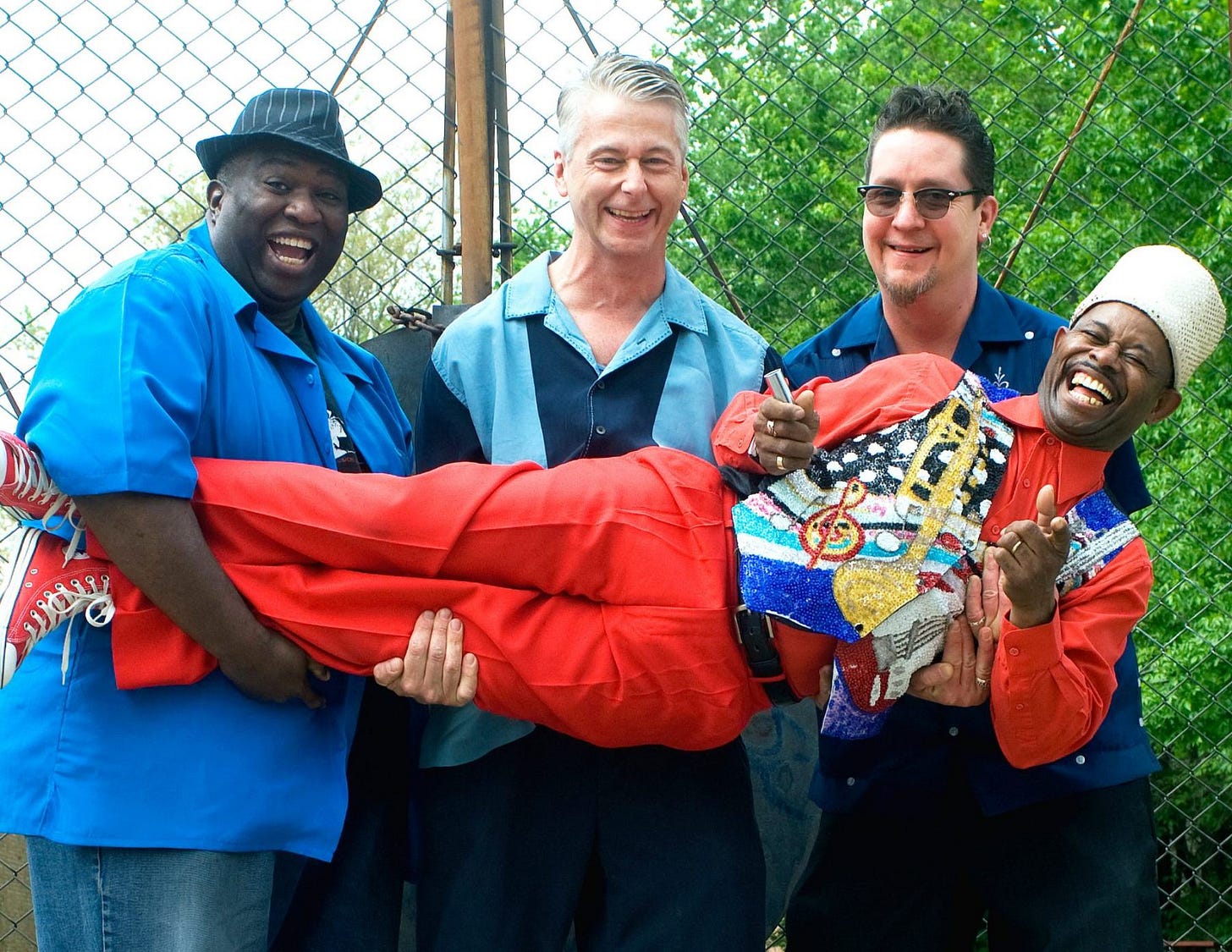 The group of Lil' Ed & The Blues Imperials stand as a group smiling and laughing with each other