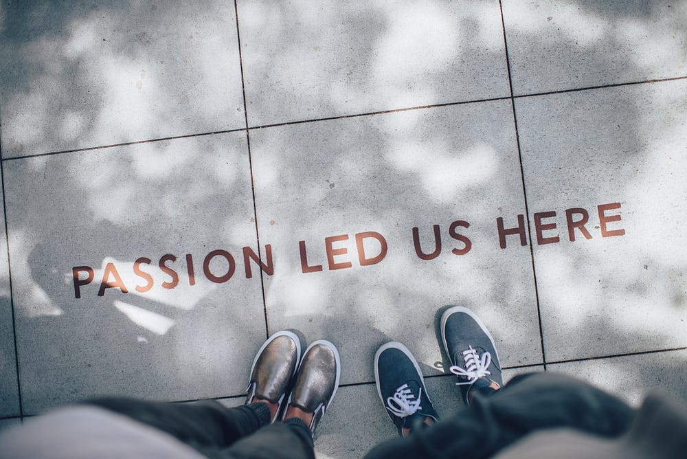 Photo of ‘Passion Led Us Here’ on the floor, next to some feet Photo of ‘Passion Led Us Here’ on the floor, next to some feet