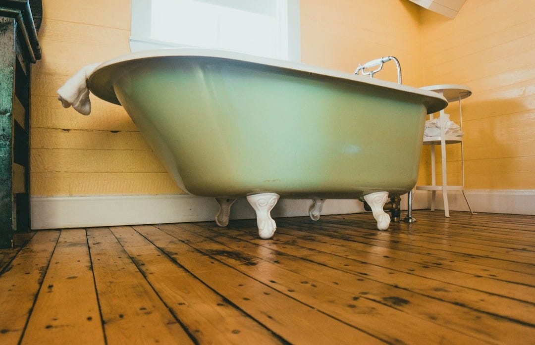white bathtub on brown wooden floor white bathtub on brown wooden floor