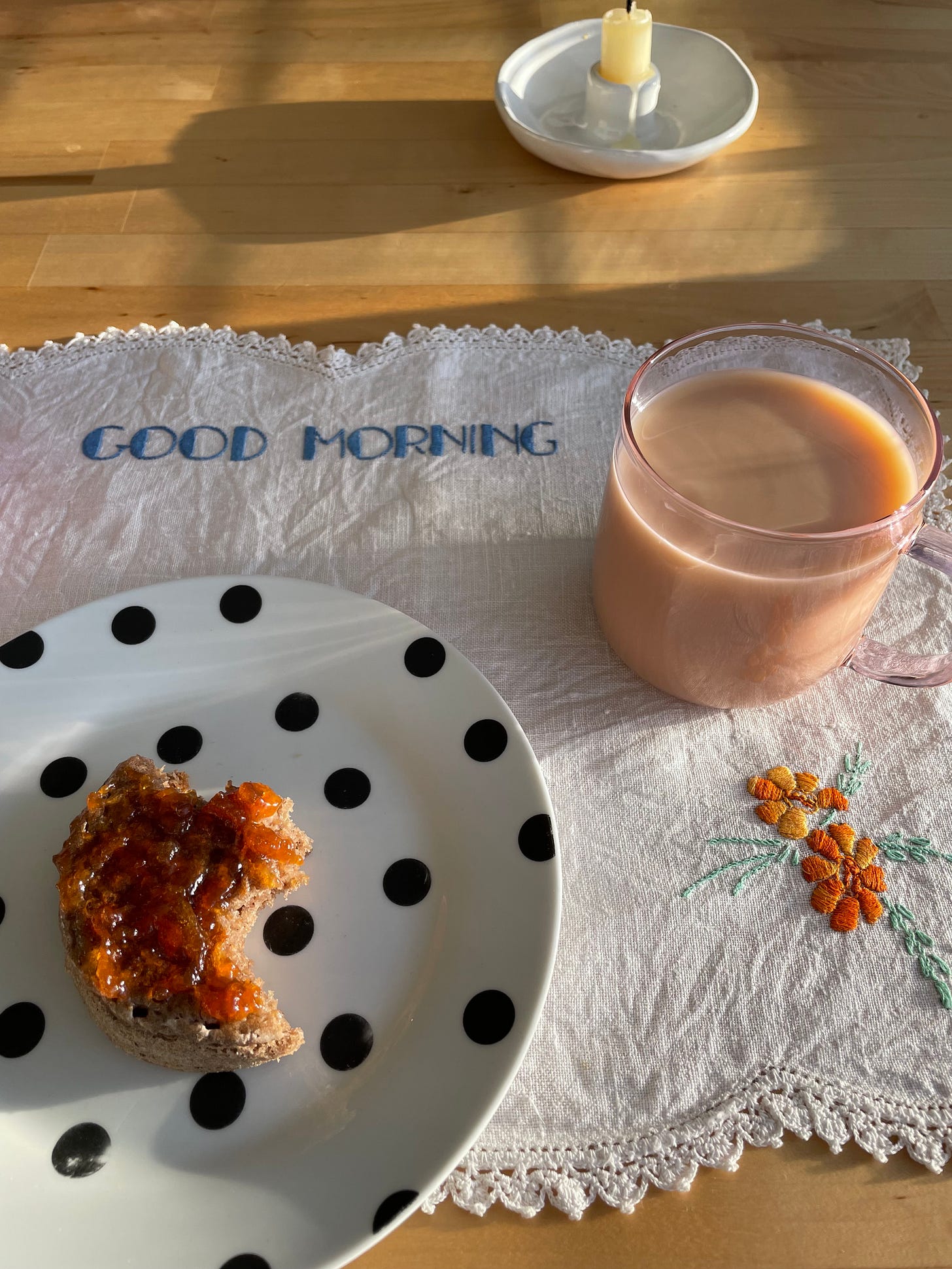 Good morning placemat with a cup of tea and a spiced winter crumpet with apricot jam.